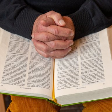 Zum Gebet gefaltete Hände liegen auf einer Bibel.