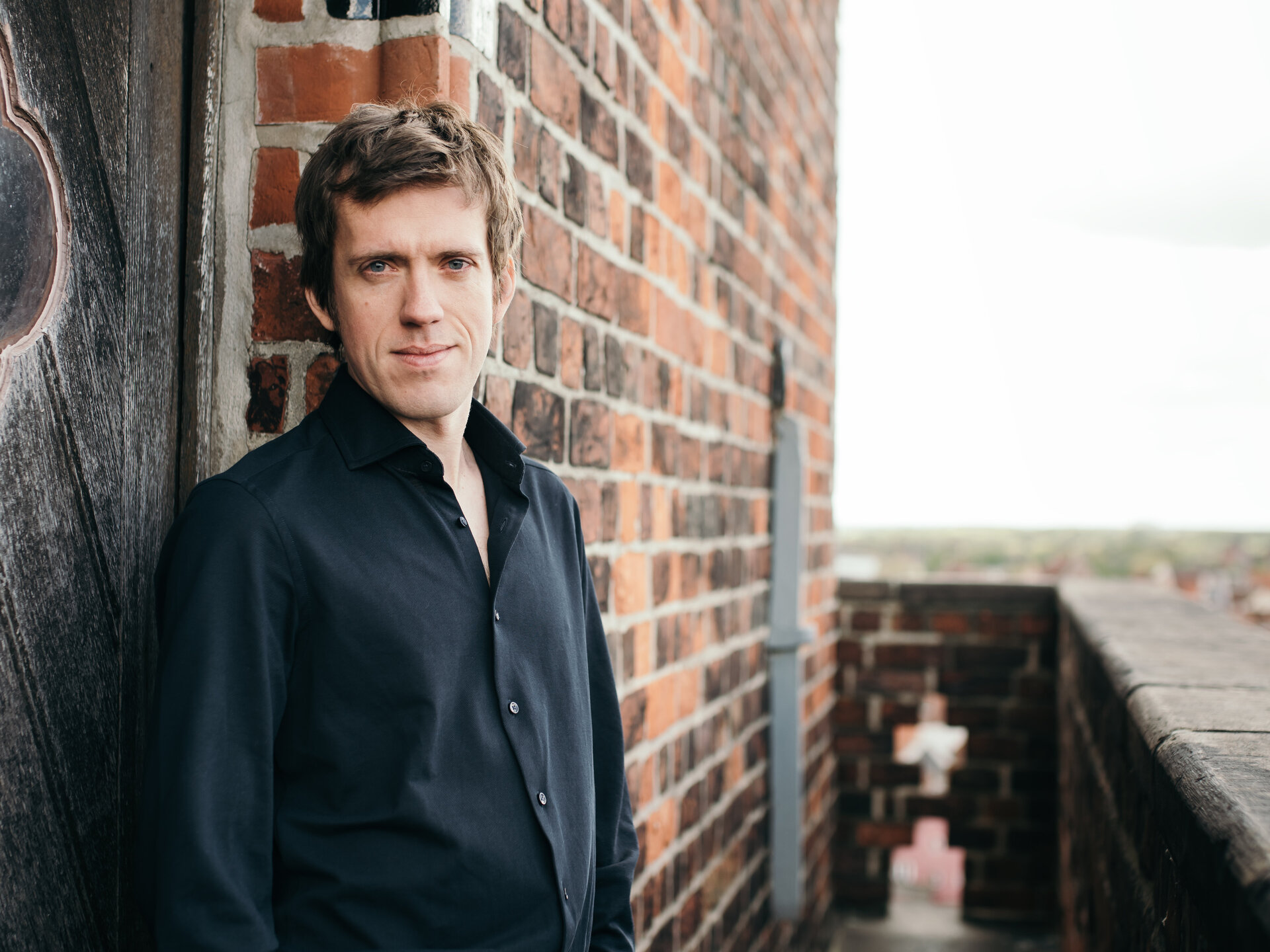 Ein Mann in schwarzem Hemd steht auf einem Kirchturm