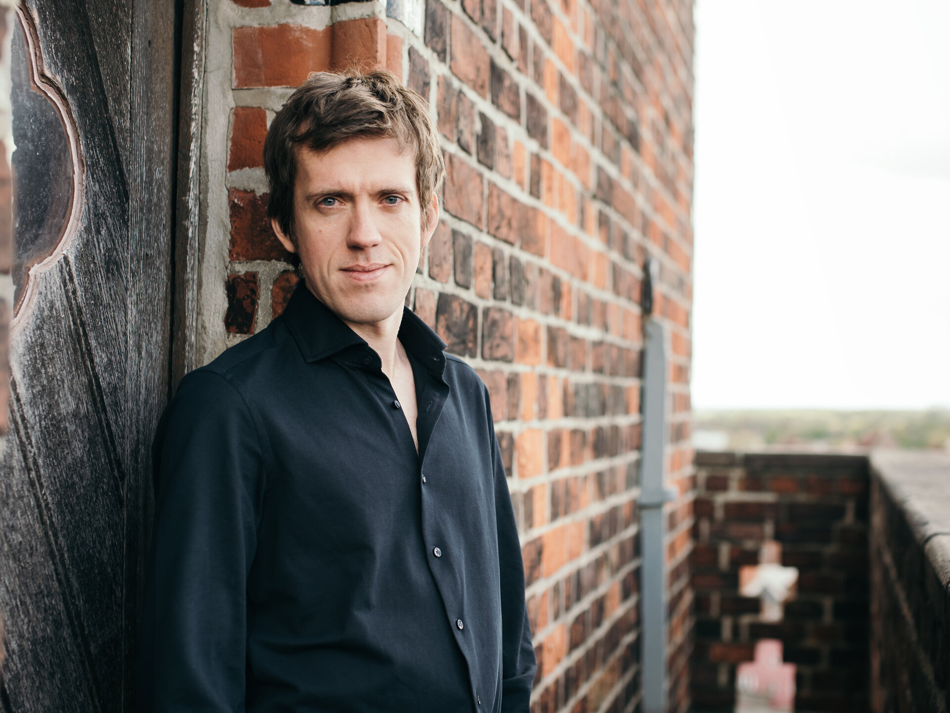 Ein Mann in schwarzem Hemd steht auf einem Kirchturm