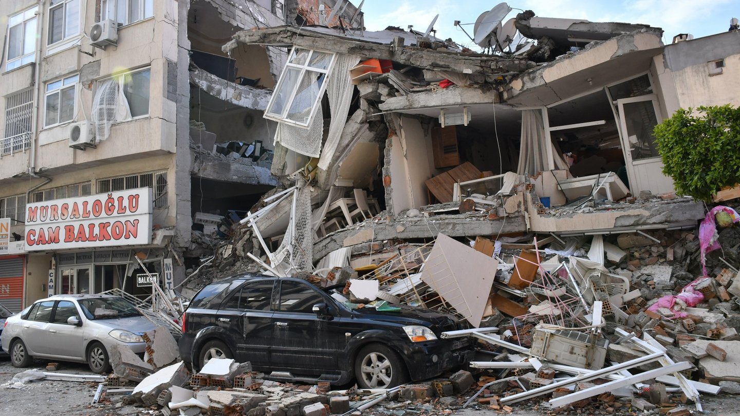 Ein eingestürztes Wohnhaus. Die Trümmer sind auf parkende Autos gefallen.