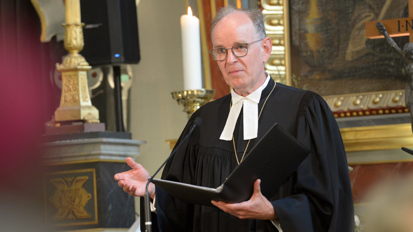 Mann im Talar in einer Kirche mit Buch in der Hand