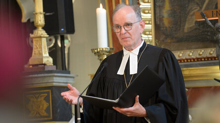 Mann im Talar in einer Kirche mit Buch in der Hand 