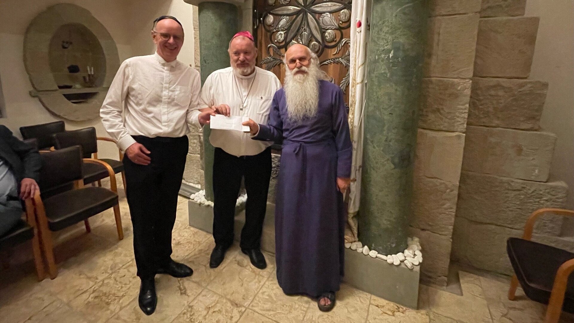 3 Männer in einem Raum ein Dokument haltend