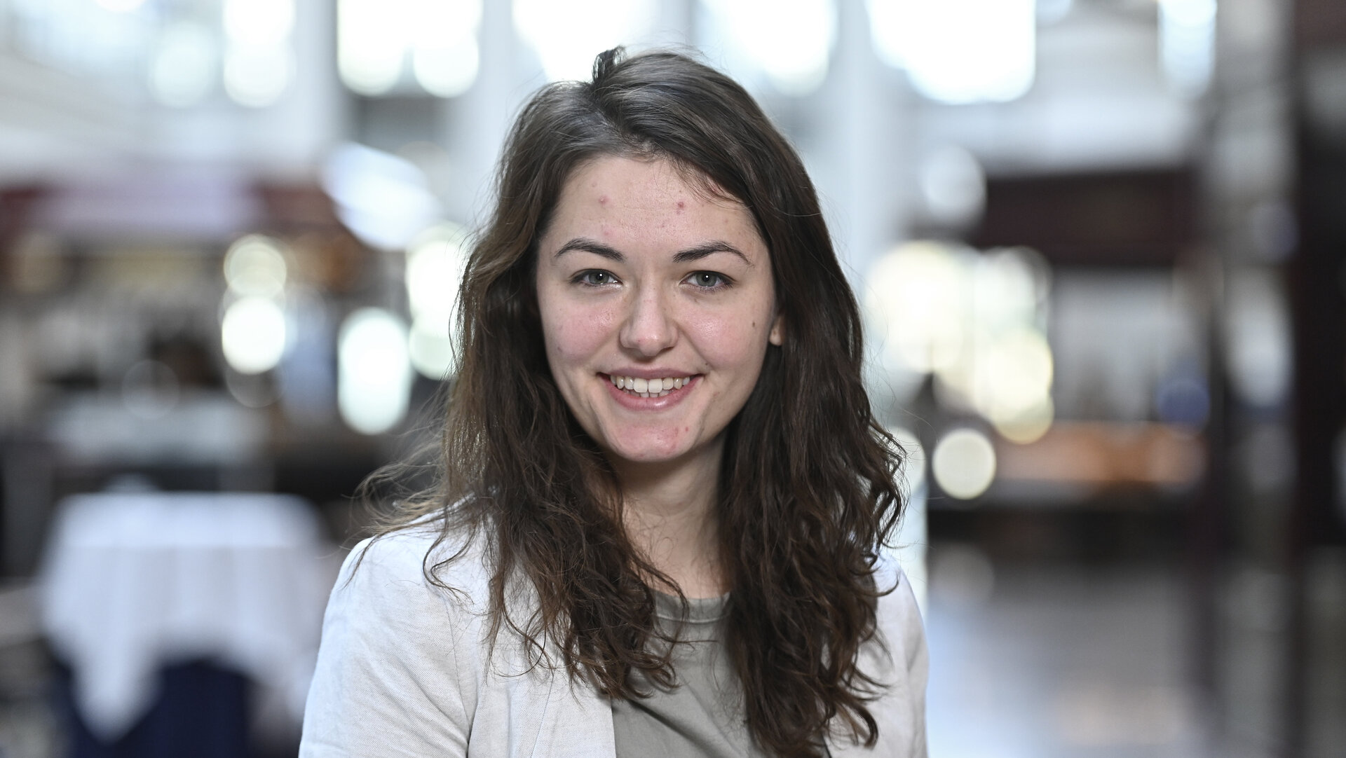 Eine junge Frau mit braunen Haaren lächelt in die Kamera.