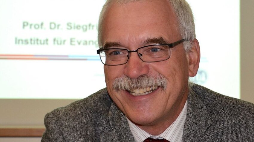 Ein Mann mit grauen Haaren, Brille und grauem Schnauzbart