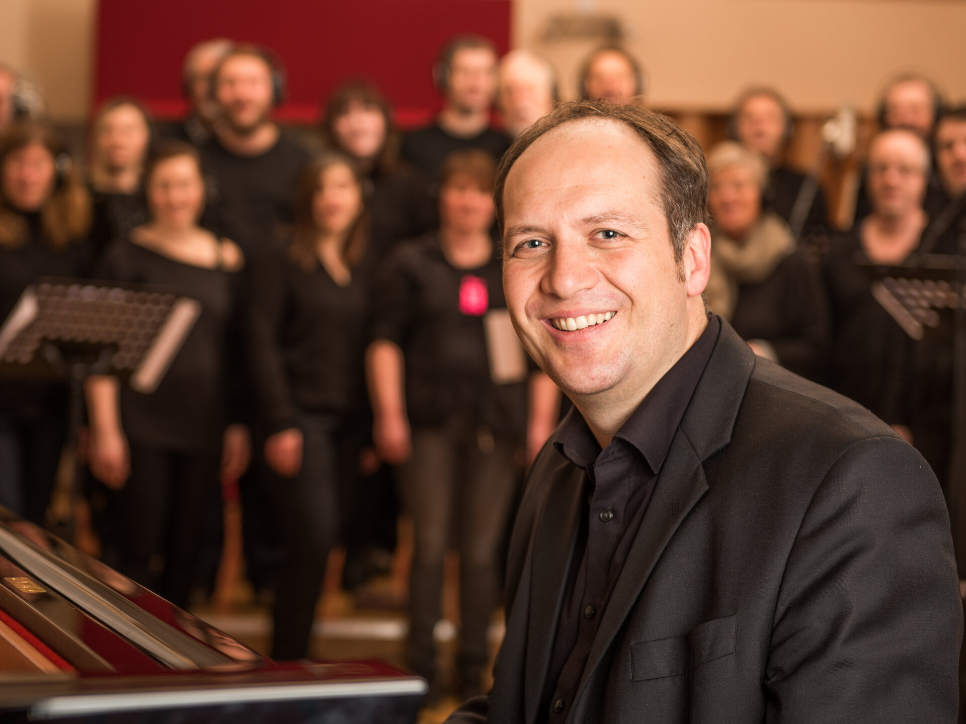 Ein Mann in schwarzem Anzug sitzt am Klavier