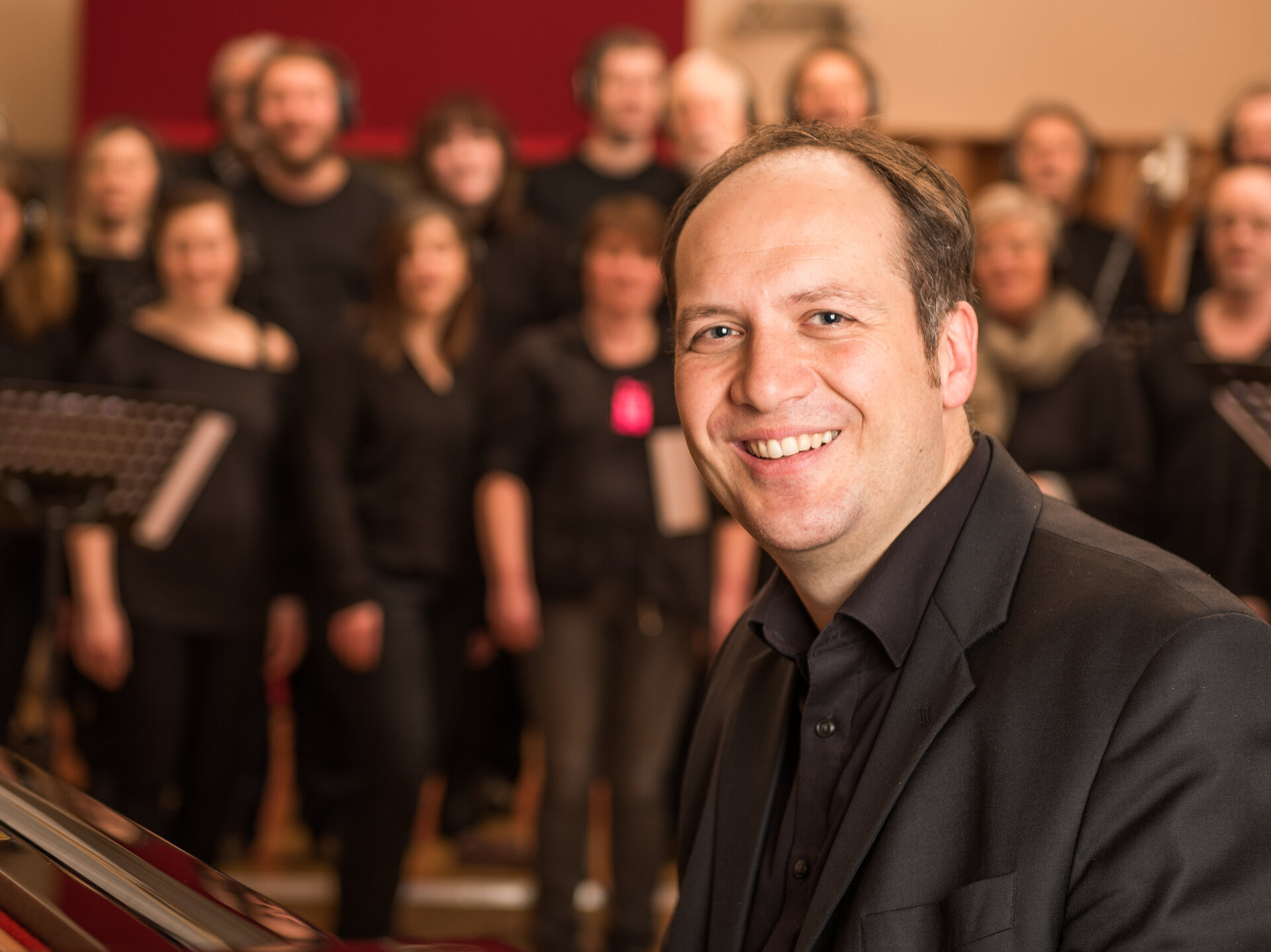 Ein Mann in schwarzem Anzug sitzt am Klavier