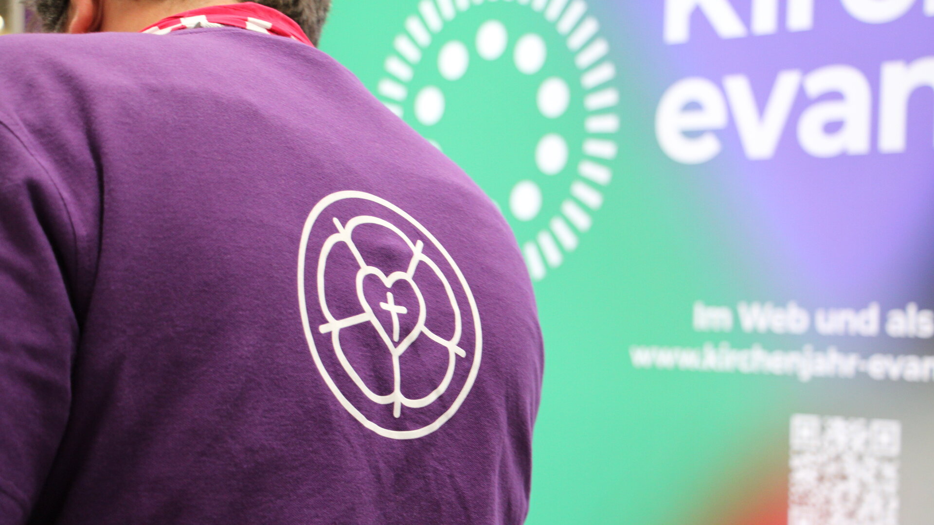 Violettes T-Shirt vor bunter Wand