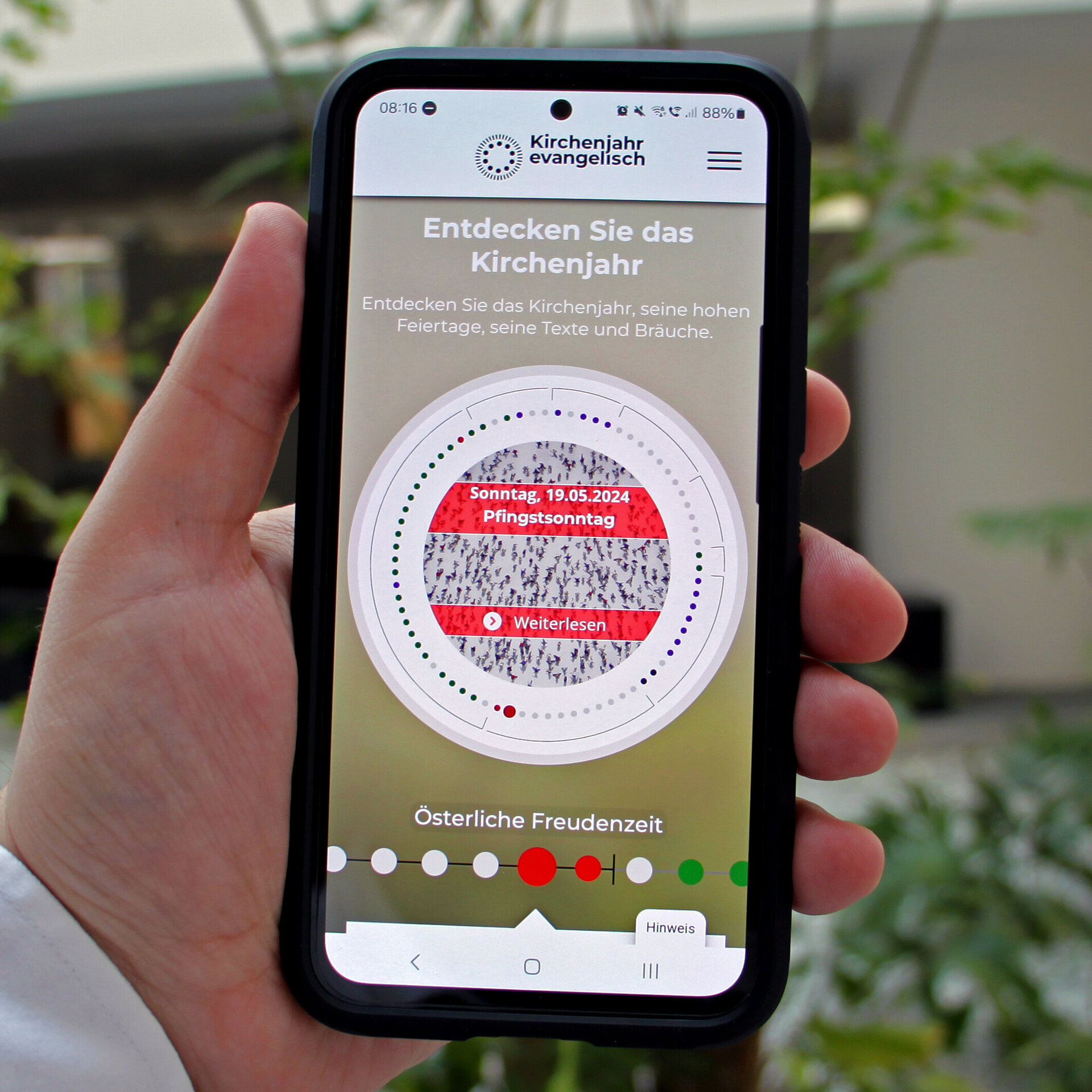 Eine Hand hält ein Smartphone, auf dem die Internetseite kirchenjahr-evangelisch.de zu sehen ist.