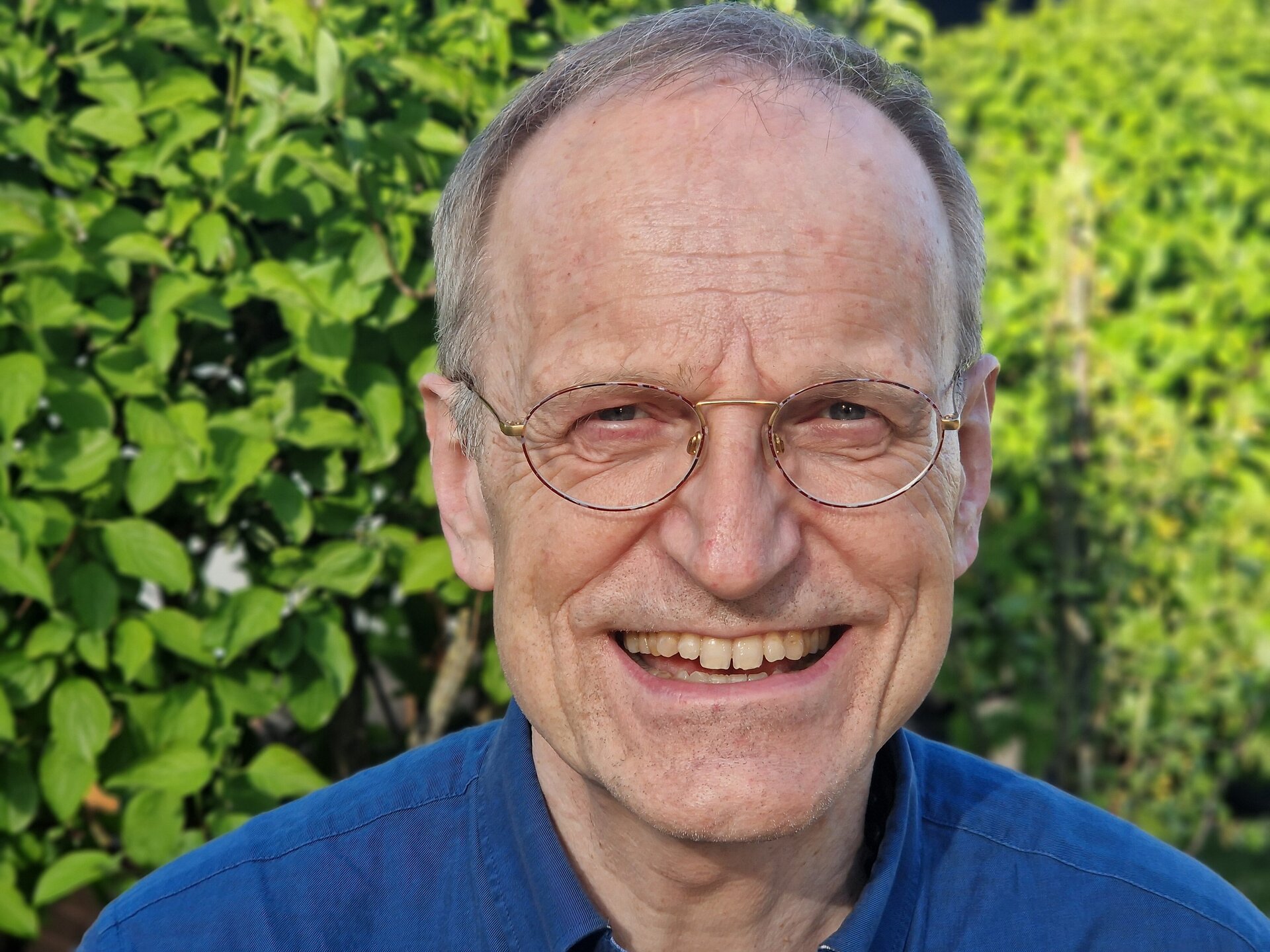 Ein älterer Mann mit Brille lächelt in die Kamera