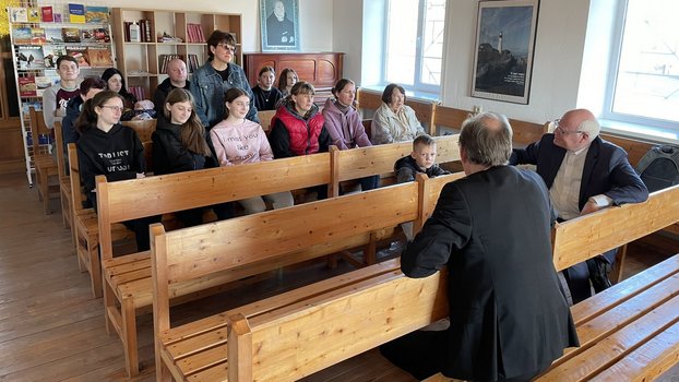 Mehrere Menschen sitzen auf den Holzbänken einer Kirche und unterhalten sich.