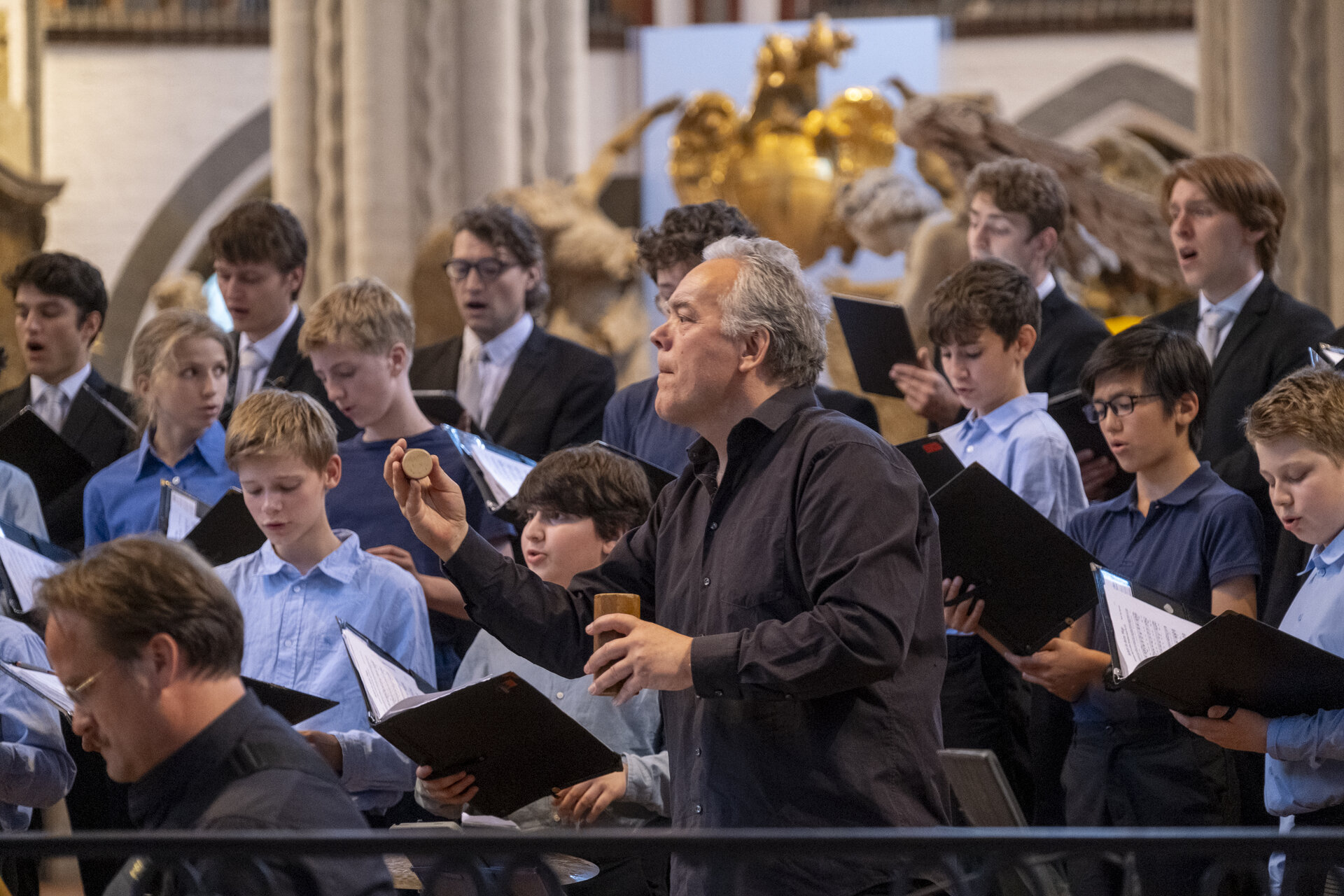 Ein Musiker mit Shakern, im Hintergrund ein Chor.